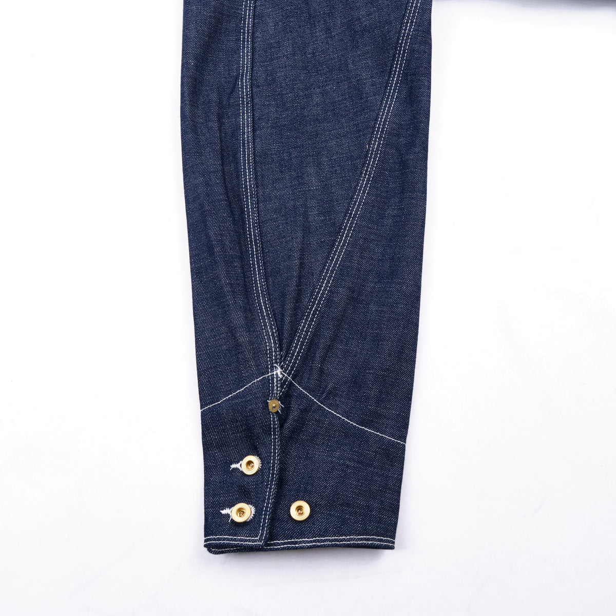 Close-up of blue denim fabric with gold buttons on a white background